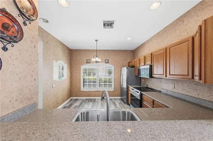 Kitchen with light wood-style flooring, stainless steel appliances, wood finish cabinetry, and hanging light fixtures