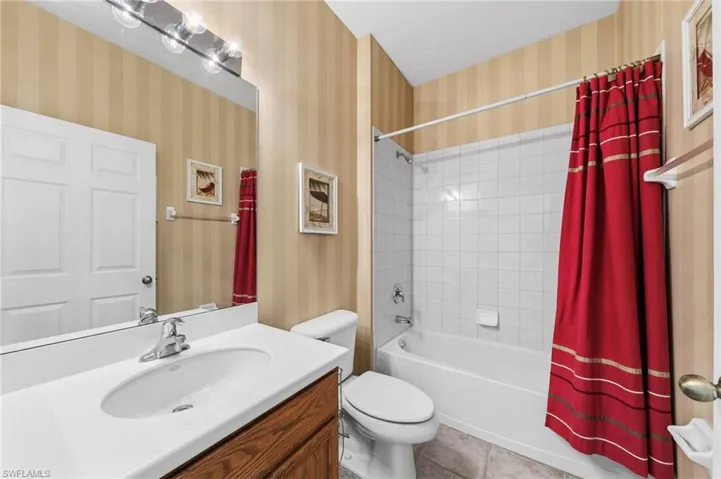 Full Guest bath featuring vanity, shower / bath combo, wallpapered walls, and light tile patterned flooring