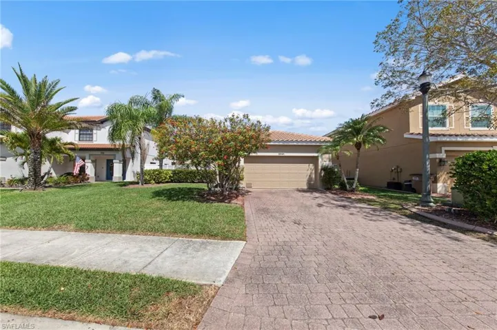 View of front of home featuring decorative driveway, a garage, stucco siding, a tile roof, and a front yard