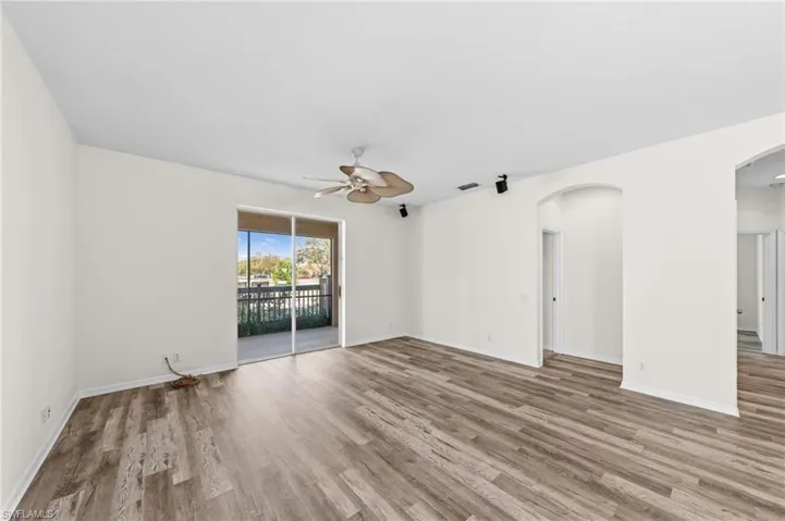 Unfurnished room featuring ceiling fan, wood finished floors, and arched walkways