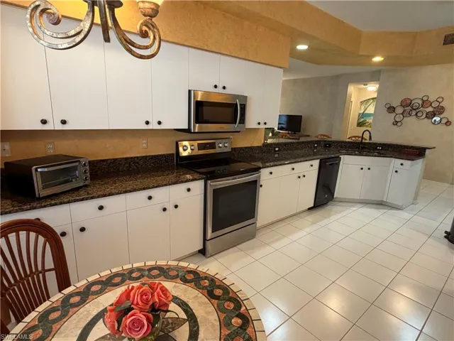 Kitchen featuring stainless steel appliances, white cabinets, a peninsula, recessed lighting, and dark stone countertops