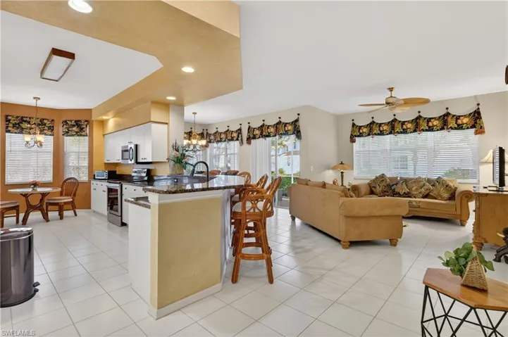 Kitchen featuring a breakfast bar area, appliances with stainless steel finishes, white cabinets, decorative light fixtures, and a chandelier