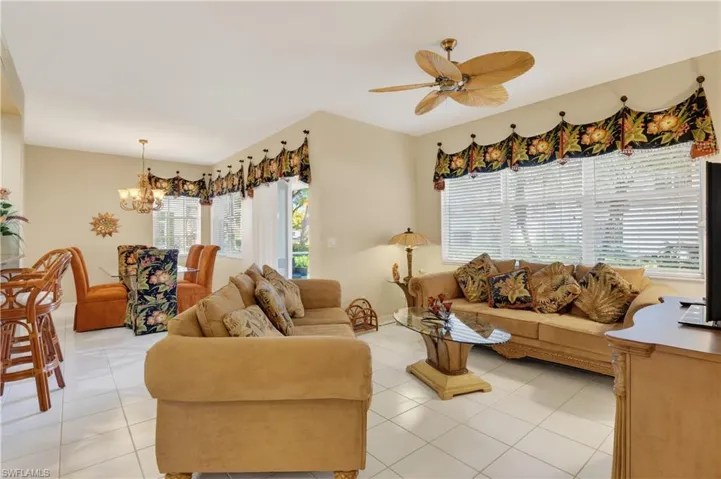 Living room featuring light tile patterned floors, a chandelier, and ceiling fan