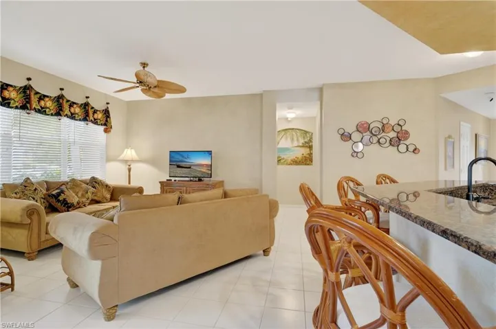 Living room with a ceiling fan and light tile patterned flooring