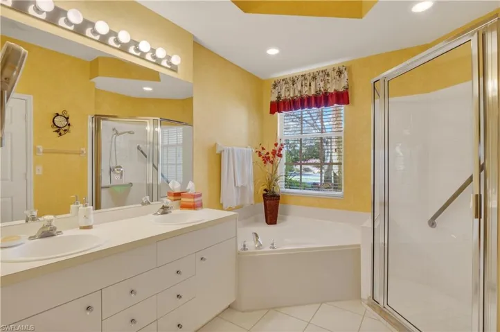 Bathroom with a stall shower, a garden tub, double vanity, light tile patterned floors, and recessed lighting