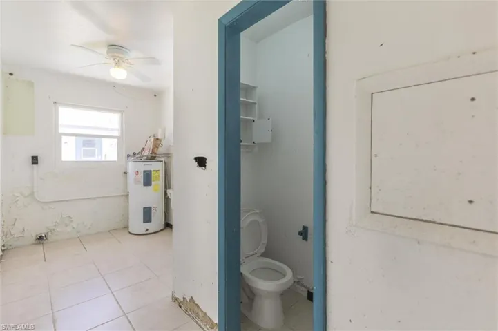 Bathroom featuring electric water heater, tile patterned floors, ceiling fan, and toilet