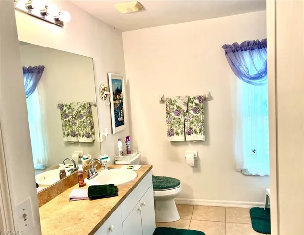 Bathroom with vanity, toilet, tile patterned floors, and plenty of natural light