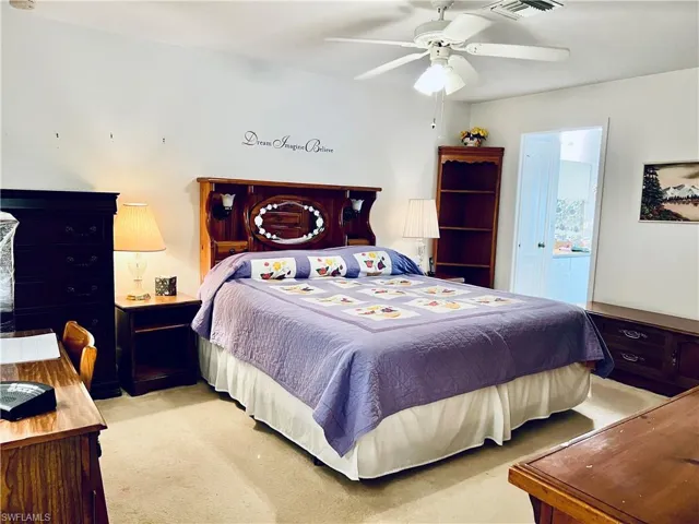 Bedroom featuring ensuite bath, light colored carpet, and ceiling fan
