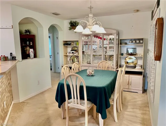 Dining room with light carpet and an inviting chandelier