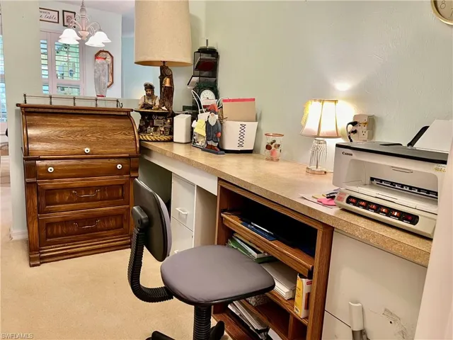 Home office featuring an inviting chandelier, light colored carpet, and built in desk