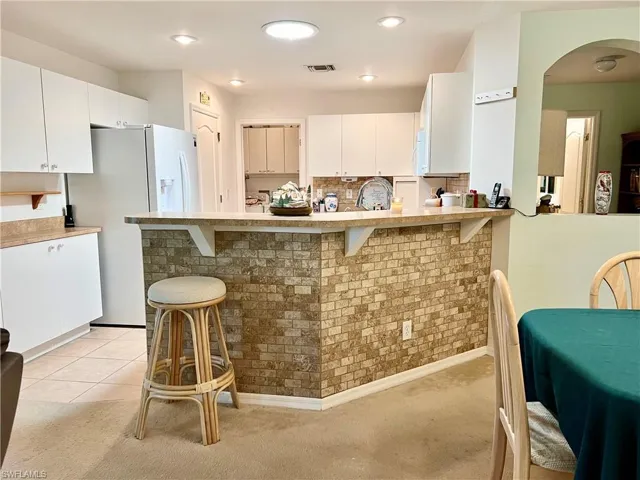 Kitchen with white cabinetry, appliances included, pantry closet and kitchen peninsula