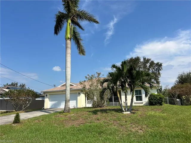 View of property hidden behind natural elements with a garage and a front lawn
