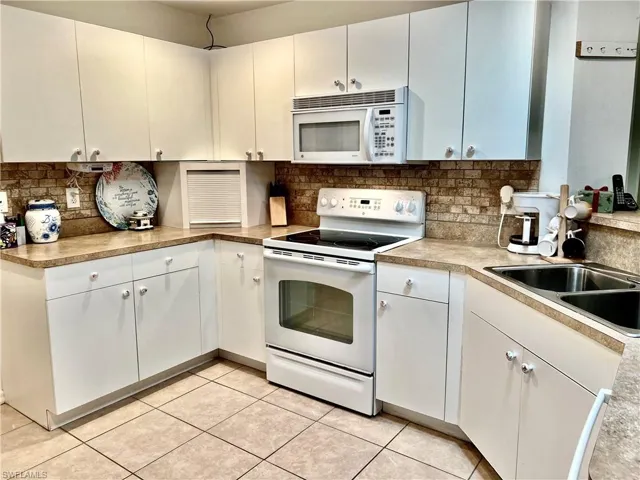 Kitchen featuring white cabinetry, white appliances, and light tile patterned floors