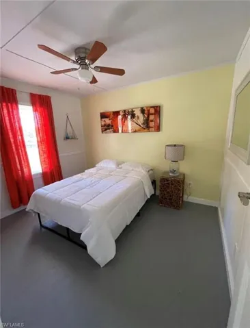 Room featuring a ceiling fan with integrated lighting, light-colored walls, and a window with red drapery