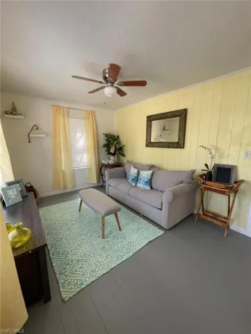 Living area featuring painted wood-finish flooring and a ceiling fan with integrated lighting