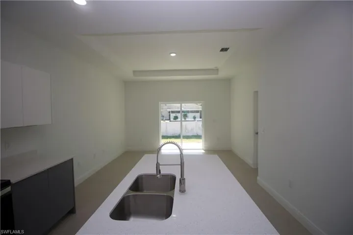 Kitchen with white cabinets, a tray ceiling, and sink