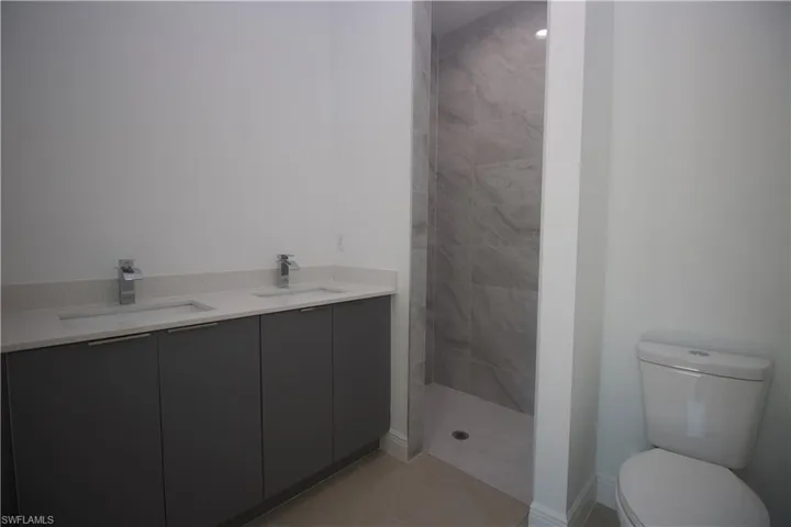 Bathroom featuring vanity, toilet, and tiled shower