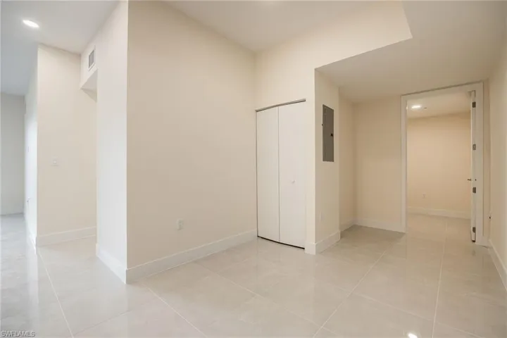 Empty room with light tile patterned flooring, electric panel, baseboards, visible vents, and recessed lighting