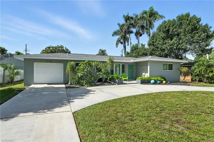 View of front facade featuring driveway, stucco siding, a garage, and a front lawn