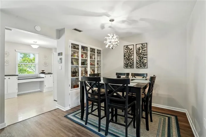 Dining room with dark wood-type flooring, a chandelier, and a desk