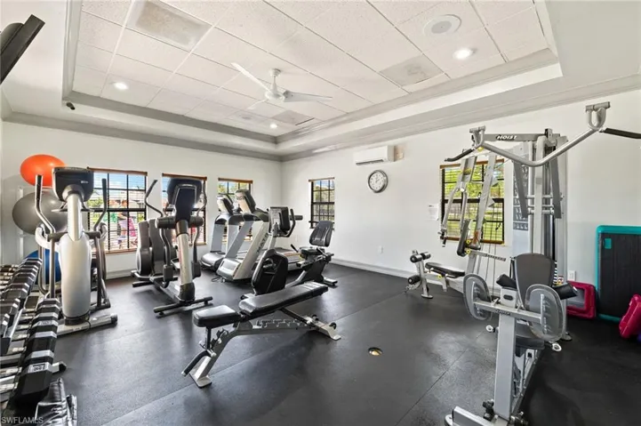 Gym with a raised ceiling, crown molding, and a wall mounted air conditioner