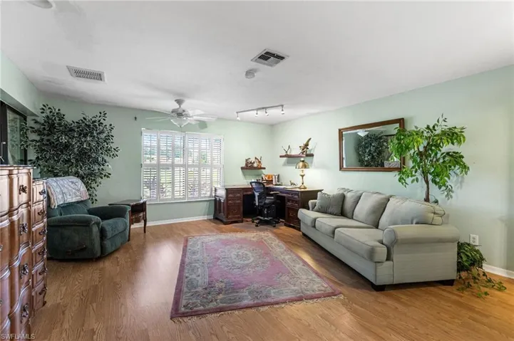 Living room featuring a desk, wood finished floors, rail lighting, and a ceiling fan