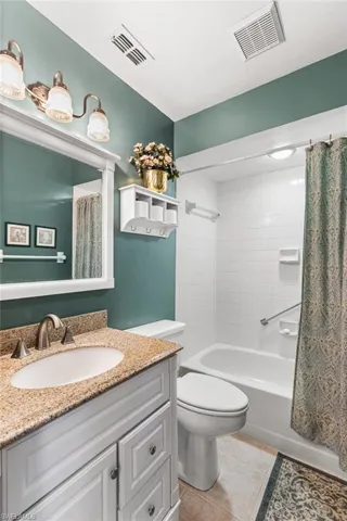 Bathroom featuring shower / bath combination with curtain, light tile patterned floors, and vanity