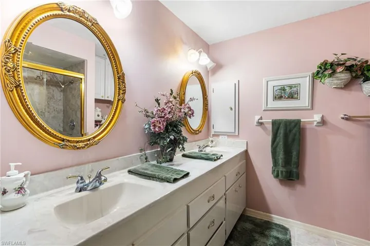 Full bath with double vanity, a shower stall, and light tile patterned floors