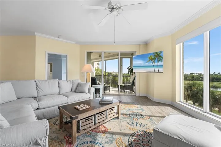 Living area with crown molding, wood finished floors, and ceiling fan