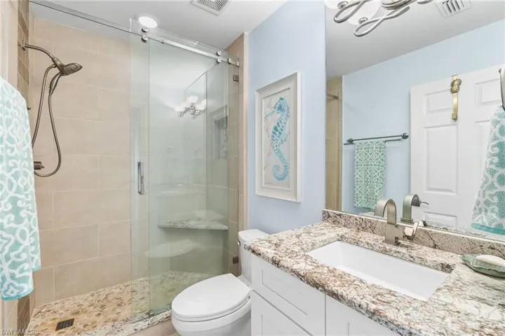 Bathroom featuring a shower stall, vanity, and a chandelier