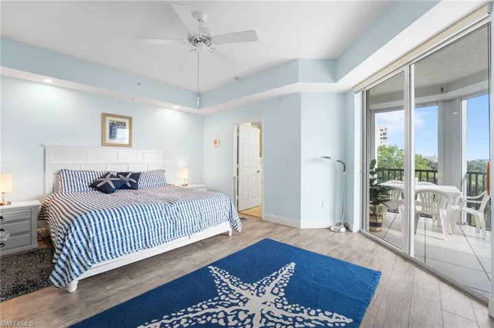 Bedroom featuring access to outside, wood finished floors, and a ceiling fan