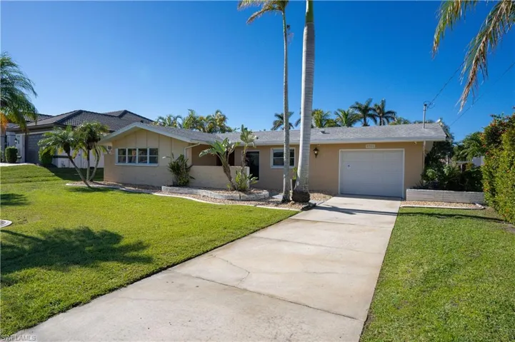 Single story home featuring a garage and a front lawn