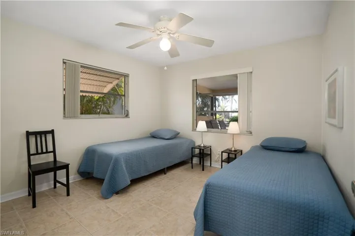 Tiled bedroom featuring multiple windows and ceiling fan