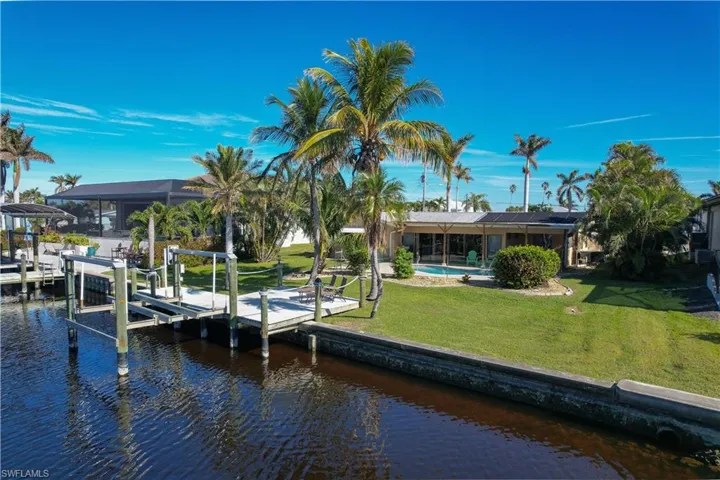 View of dock featuring a water view, a yard, and a pool