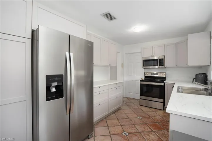 Kitchen featuring white cabinets, appliances with stainless steel finishes, tile patterned floors, and sink