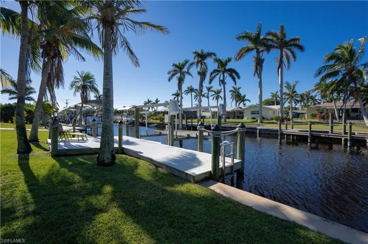 View of dock with a lawn and a water view
