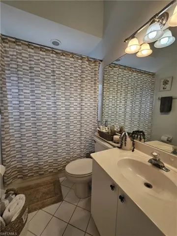Bathroom featuring light tile patterned floors, vanity, and a shower with shower curtain