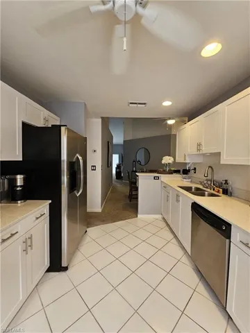 Kitchen with white cabinetry, backsplash, light stone countertops, stainless steel appliances, and recessed lighting