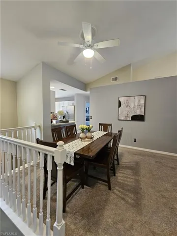 Dining area featuring dark carpet, vaulted ceiling, and a ceiling fan