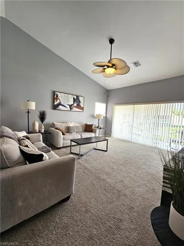 Living area with carpet floors, vaulted ceiling, and a ceiling fan