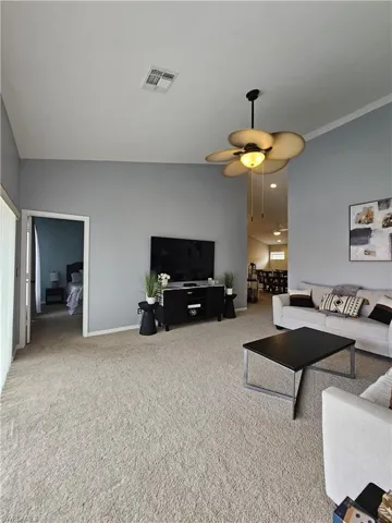 Carpeted living room with baseboards and a ceiling fan