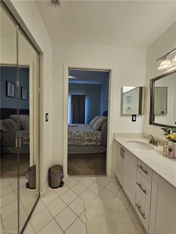 Ensuite bathroom with vanity and light tile patterned floors