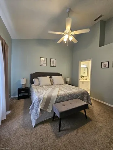 Bedroom with carpet floors, ceiling fan, and ensuite bathroom