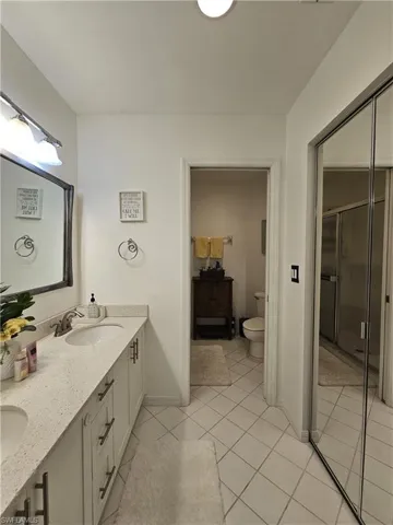 Full bath with double vanity, light tile patterned floors, and a stall shower