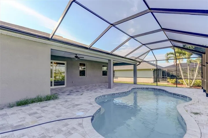 View of swimming pool with glass enclosure, a patio area, and ceiling fan