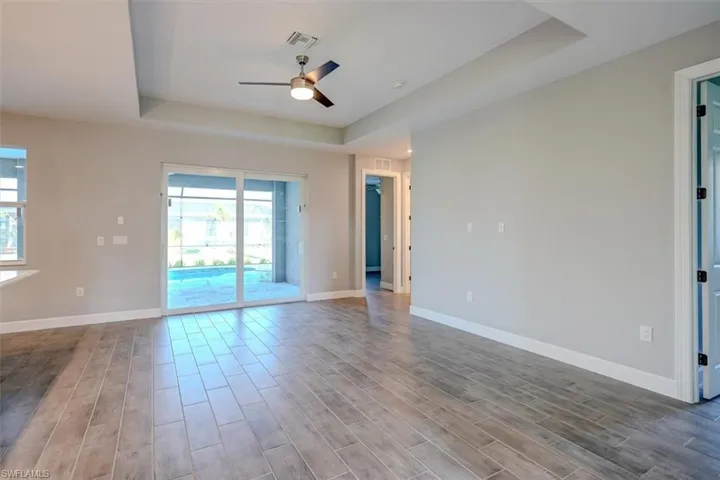 Spare room with hardwood / wood-style flooring, ceiling fan, and a raised ceiling