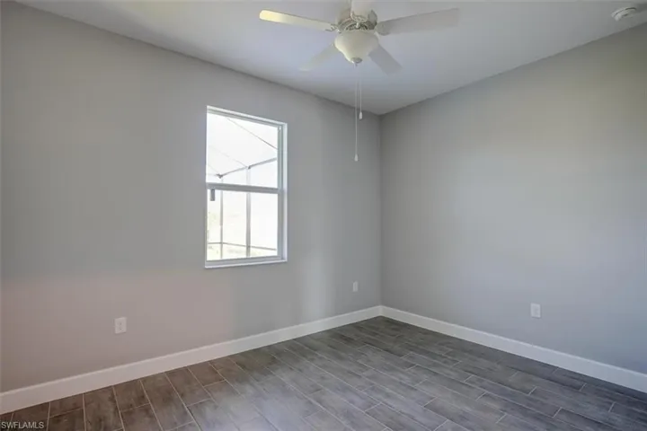 Empty room featuring dark wood-type flooring and ceiling fan