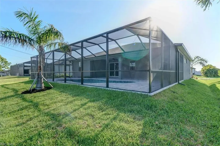 Back of house with a yard, a pool, and a lanai