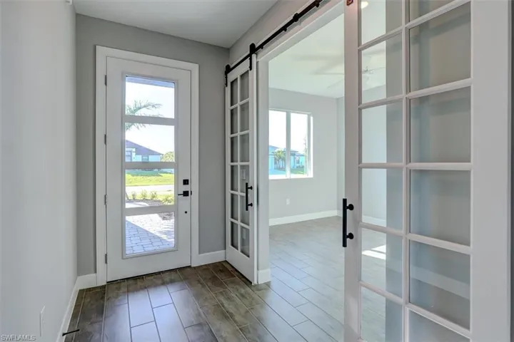 Doorway with a barn door, french doors, a wealth of natural light, and wood-type flooring