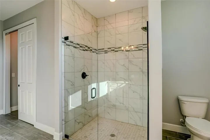 Bathroom with walk in shower, tile flooring, and toilet